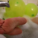 feet in a bathtub with green balloons